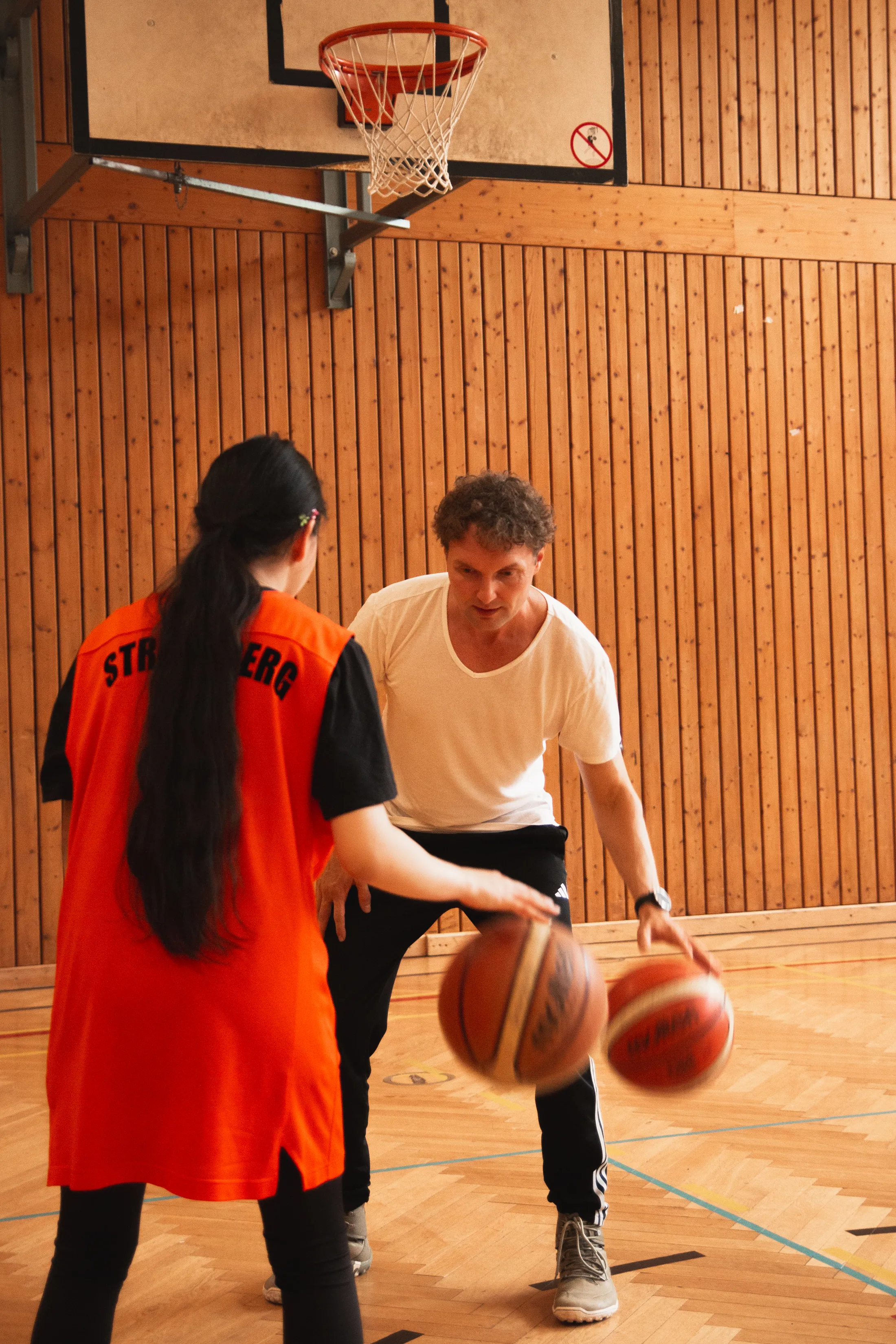 Stephan Blumenthal mit jugendlicher Basketballerin in der Sporthalle beim Training