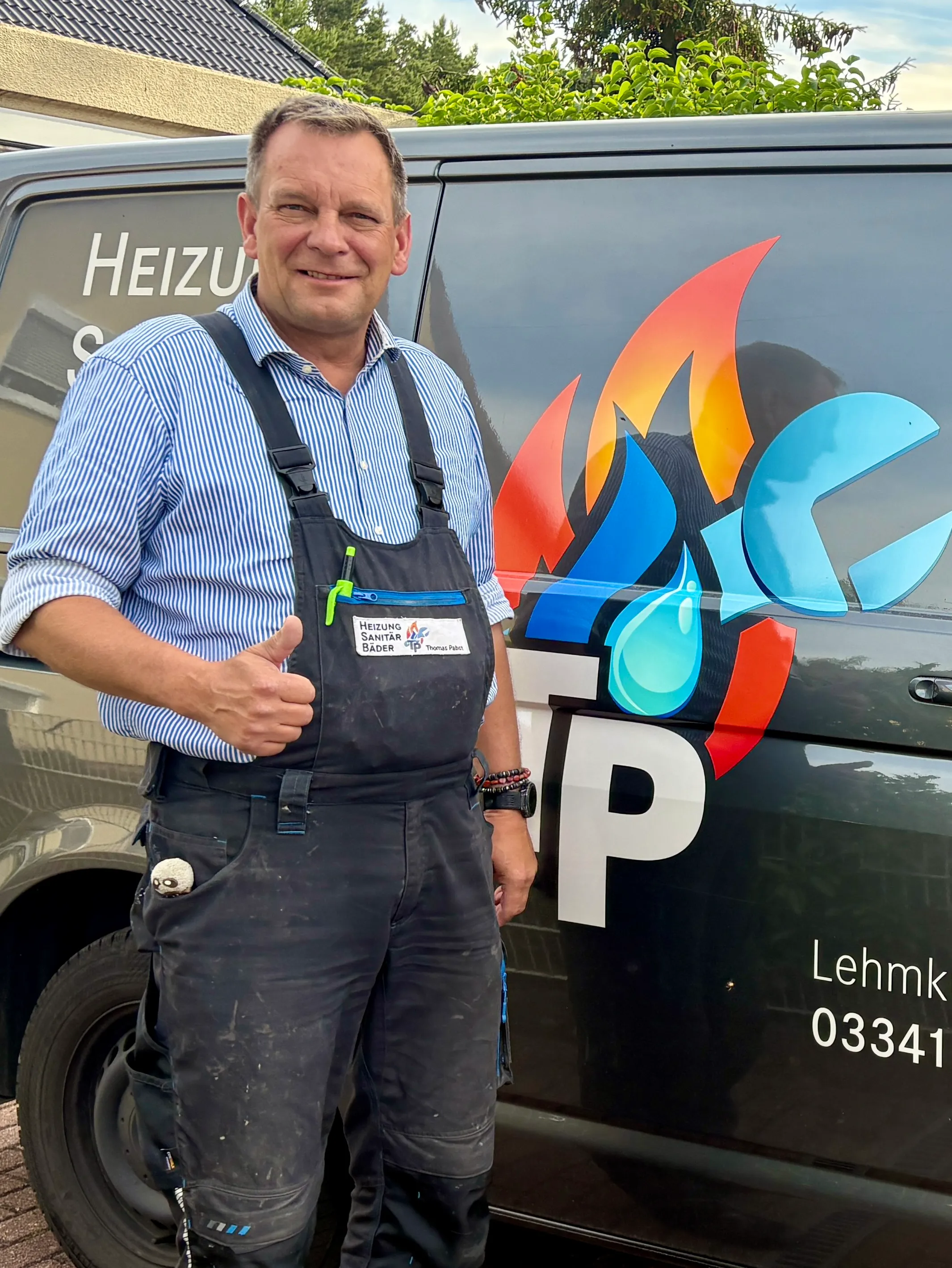 Handwerker Thomas Papst vor seinem Arbeitsfahrzeug in Arbeitskleidung