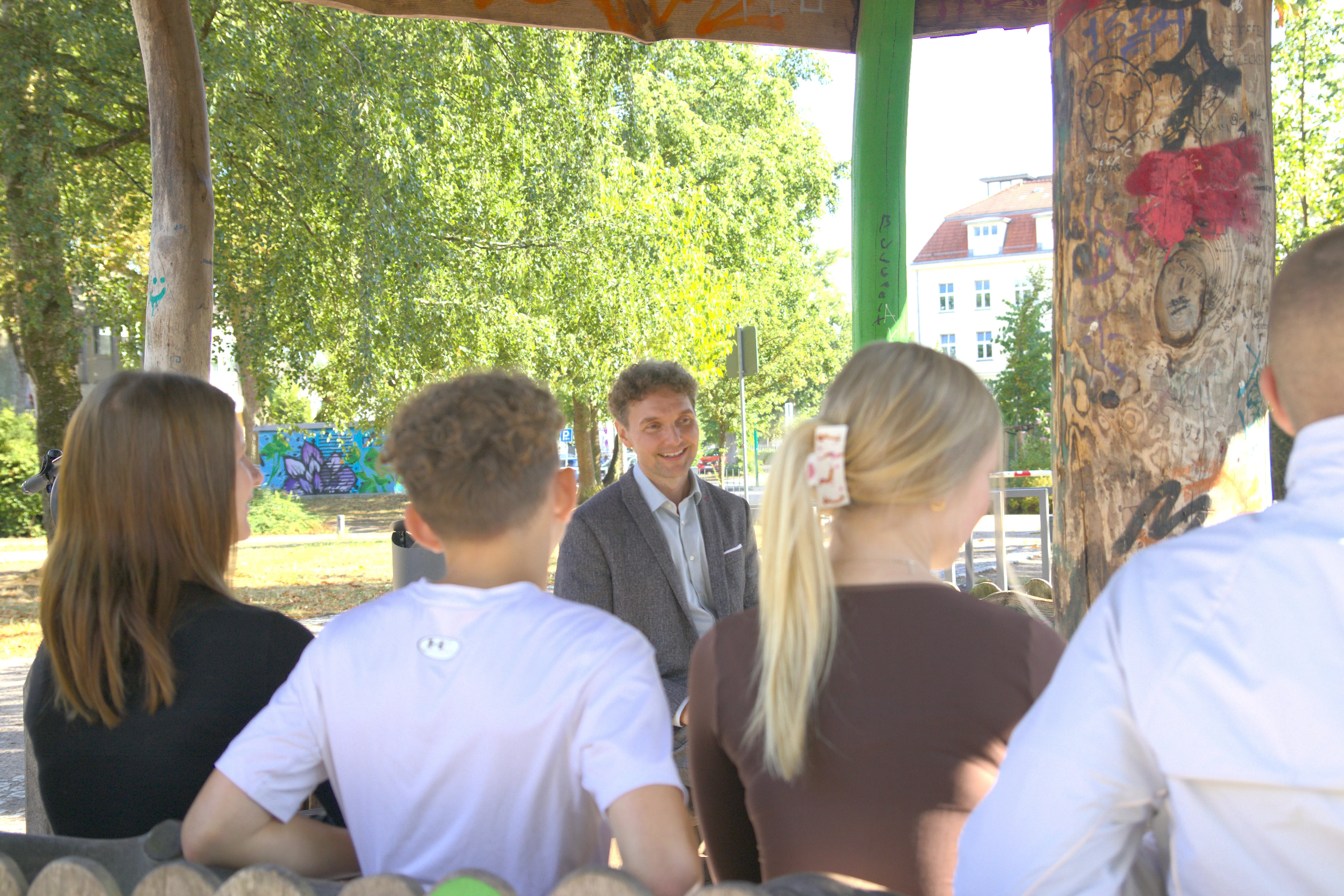 Jugendliche im Gespräch mit Stephan Blumenthal draußen bei gutem Wetter